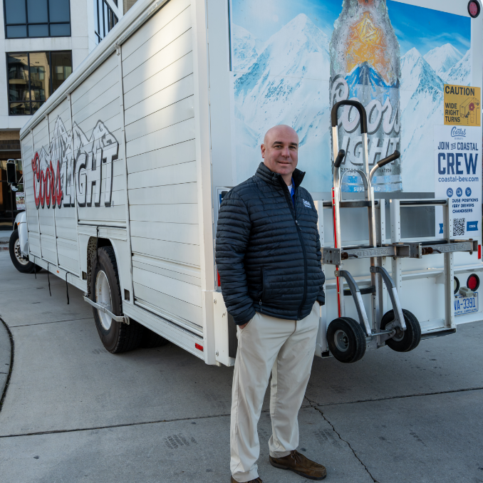 Employee smiling standing in front of a Coors Light truck