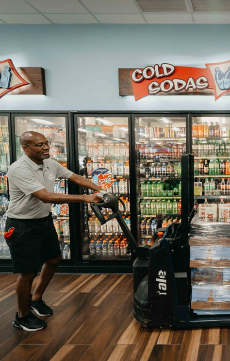LongBev15_Desktop Employee pushing cases of beer into the beer section of a store